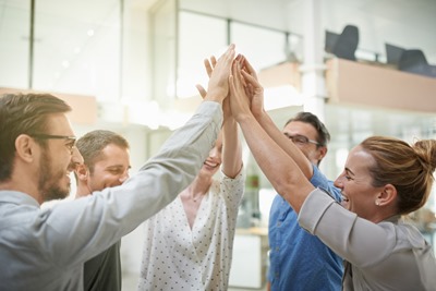 Shot of a team of colleagues celebrating with a high five in a modern office