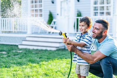 Father splashing water and having fun with son on back yard